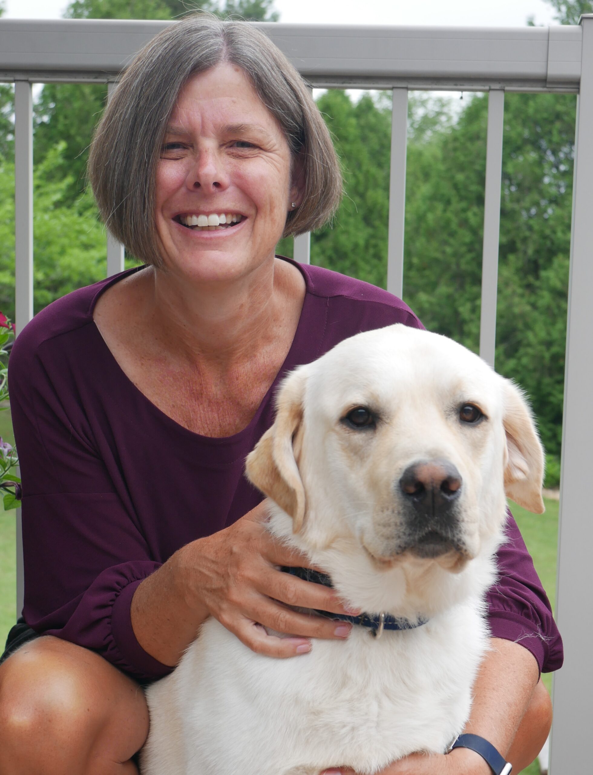 Heather Weese kneeling beside her yellow Labrador Retriever