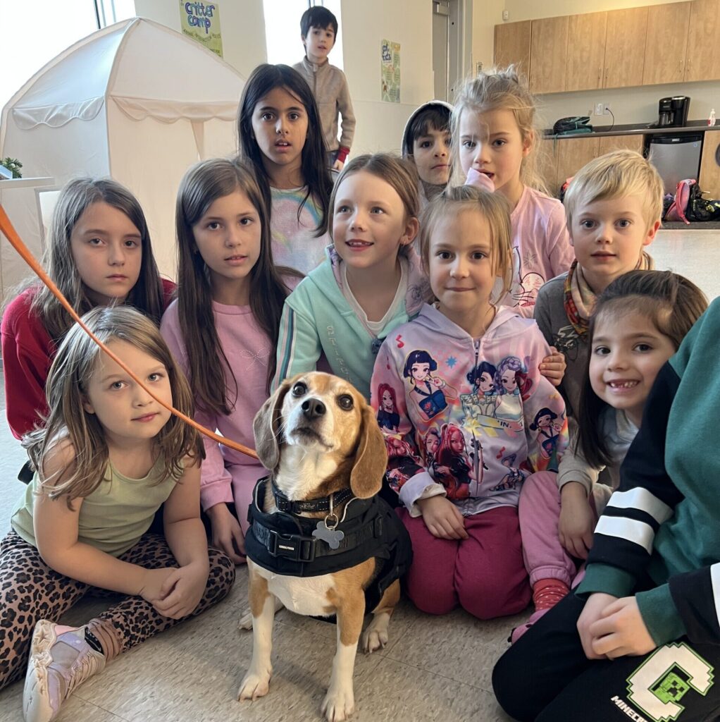 A group of children sitting with a beagle during a GHS Critter Camp session.